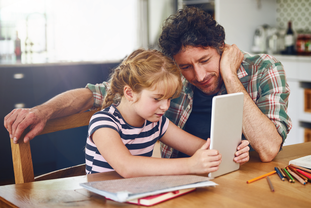 Canadian child smiling while correcting a math worksheet mistake with parent encouragement